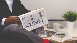 man-reading-newspaper-while-sitting-near-table-with-935979